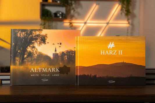 ALTMARK und HARZ II als Bildband-Set: Beide Bücher mit ihren Landschaftscovern nebeneinander auf einem Holztisch im warmen Abendlicht.